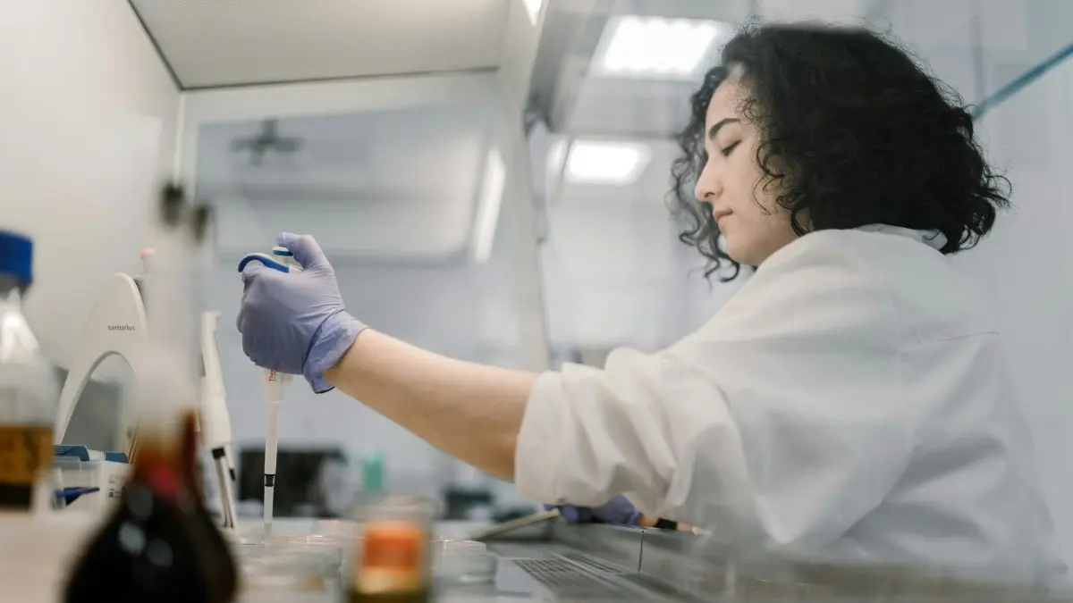 Femme scientifique manipulant un échantillon dans un laboratoire.